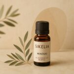olio essenziale niaouli benefici: flacone in vetro ambrato con foglie verdi, rappresentazione elegante e naturale
